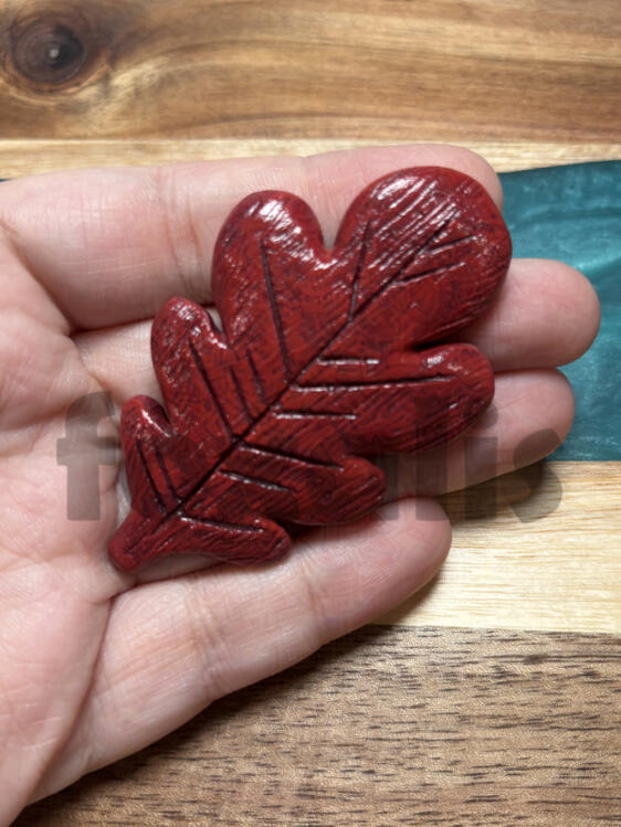 A photo of a sculpted and cast leaf painted in red.