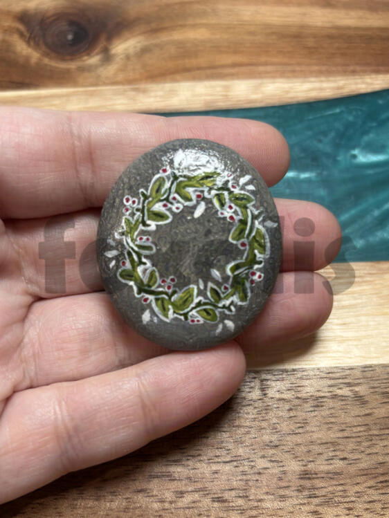 A photo of a rock painted with a green and white wreath on it.